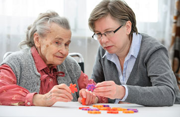 Daughter helping elderly mother with puzzle