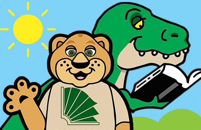 ASCPL mascot Paws with a dinosaur reading a book